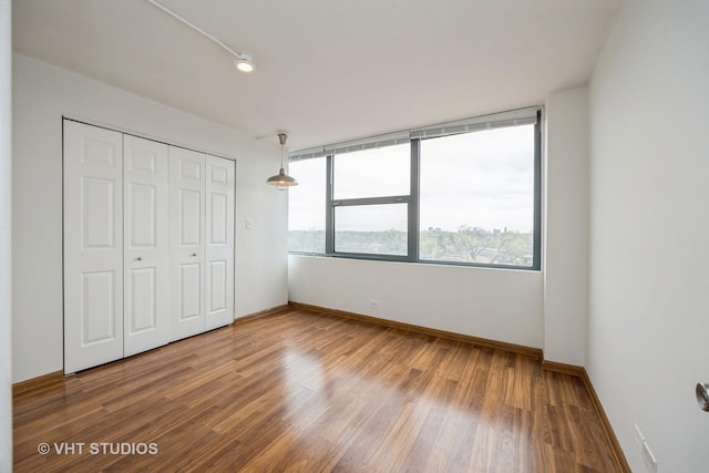unfurnished bedroom featuring baseboards, a closet, and wood finished floors