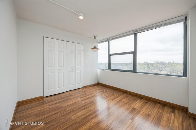 unfurnished bedroom with baseboards, a closet, and wood finished floors