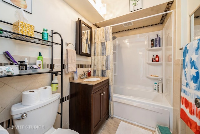 full bathroom featuring toilet, shower / tub combo, tile walls, visible vents, and vanity