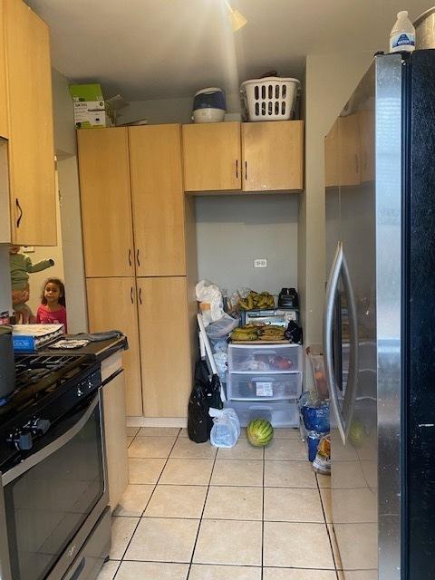 kitchen with light brown cabinets, stainless steel appliances, and light tile patterned flooring