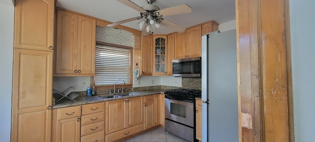 kitchen with dark stone counters, sink, ceiling fan, tasteful backsplash, and stainless steel appliances