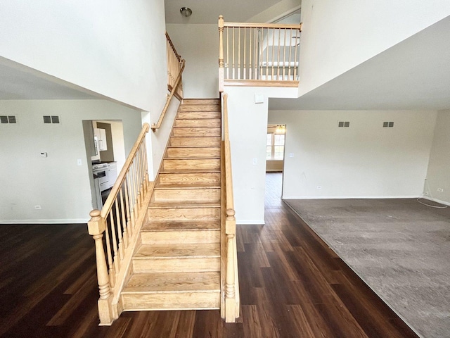 stairs with hardwood / wood-style floors and a towering ceiling