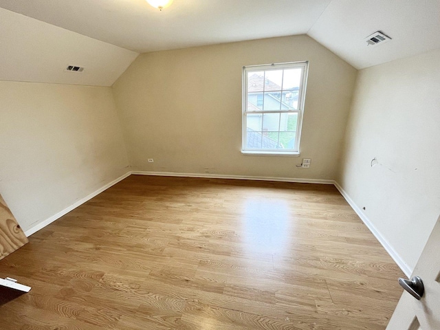 additional living space with vaulted ceiling and light hardwood / wood-style flooring