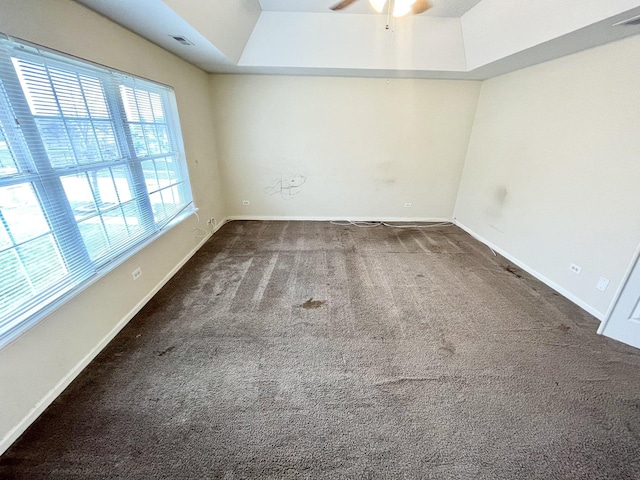 carpeted spare room featuring a tray ceiling and ceiling fan