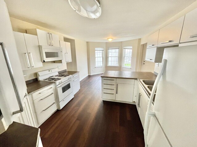 kitchen featuring kitchen peninsula, white appliances, dark hardwood / wood-style floors, and white cabinetry