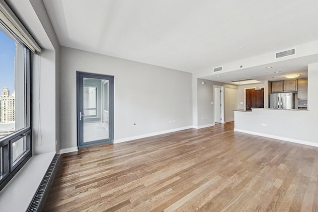 unfurnished living room featuring a wealth of natural light and wood-type flooring