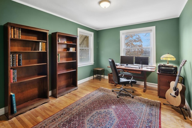 office space with light wood-type flooring, baseboards, and crown molding