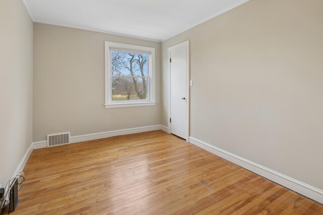 empty room with visible vents, light wood-style flooring, and baseboards