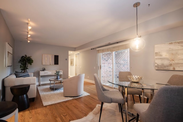 dining area featuring rail lighting and light hardwood / wood-style flooring