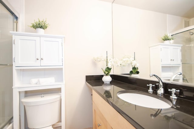 bathroom with vanity, a shower with shower door, and toilet