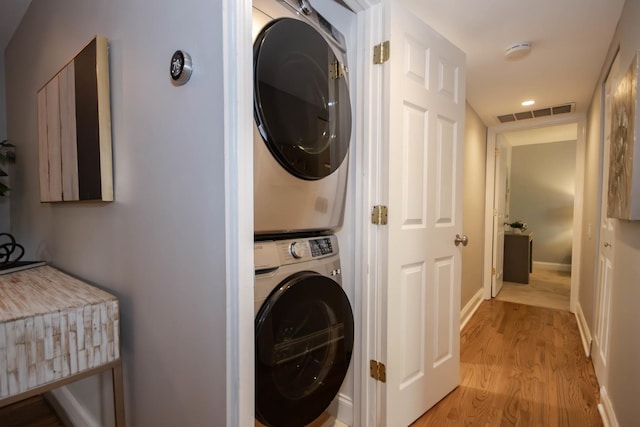 laundry room with light hardwood / wood-style floors and stacked washer and clothes dryer