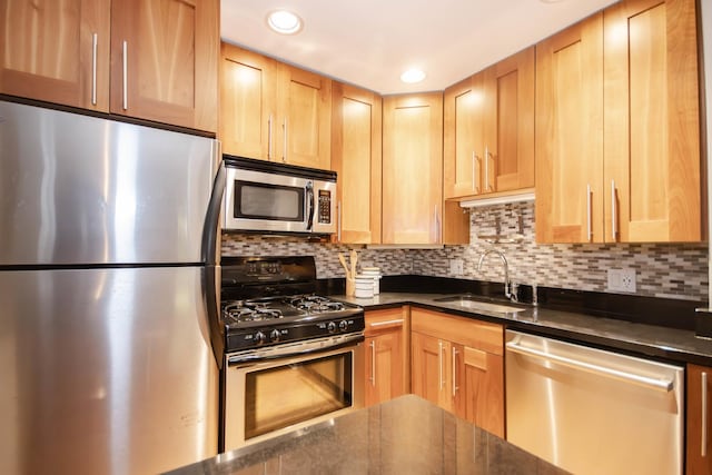 kitchen with backsplash, dark stone countertops, sink, and appliances with stainless steel finishes