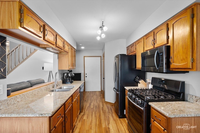 kitchen with light stone countertops, light wood-type flooring, gas stove, and sink