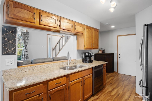 kitchen featuring sink, dishwasher, light stone counters, light hardwood / wood-style flooring, and stainless steel fridge