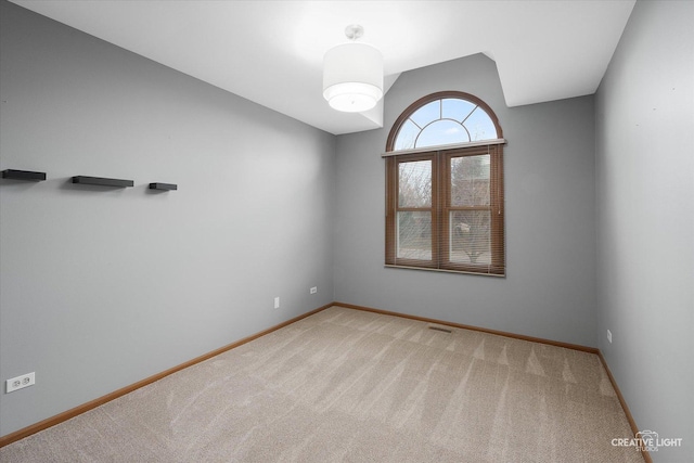 carpeted spare room featuring lofted ceiling