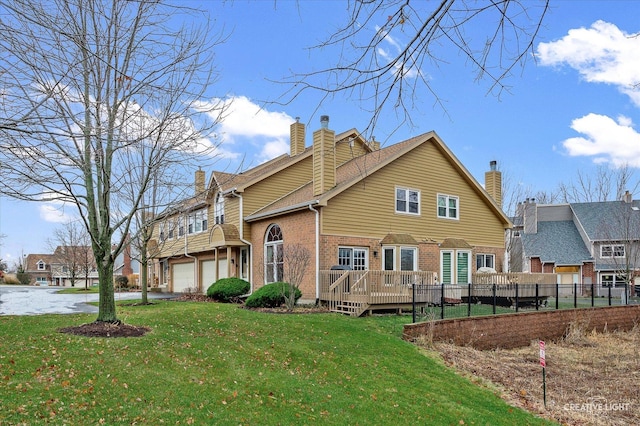 rear view of house with a yard, a garage, and a wooden deck