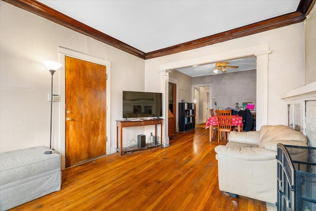 living room with hardwood / wood-style floors, decorative columns, ceiling fan, and crown molding