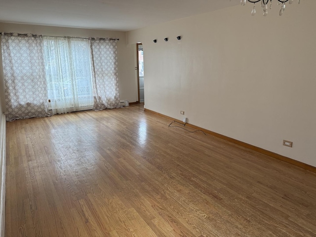 spare room with wood-type flooring and a chandelier