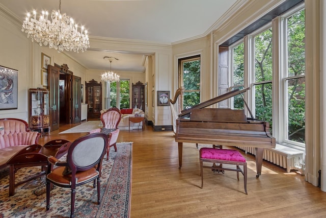 living area featuring ornamental molding, an inviting chandelier, radiator, and light hardwood / wood-style floors