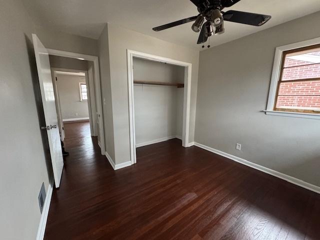 unfurnished bedroom with dark wood-type flooring, ceiling fan, and a closet