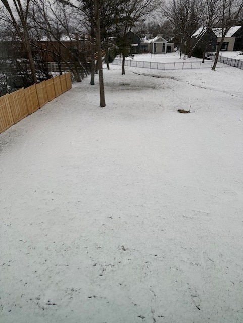 yard layered in snow featuring fence and a residential view