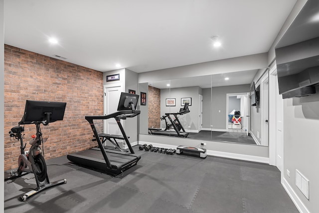 workout room with recessed lighting, baseboards, visible vents, and brick wall