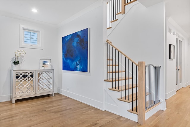 staircase with ornamental molding, recessed lighting, wood finished floors, and baseboards