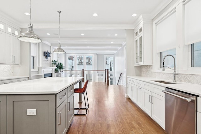 kitchen with backsplash, white cabinets, sink, dishwasher, and a kitchen island