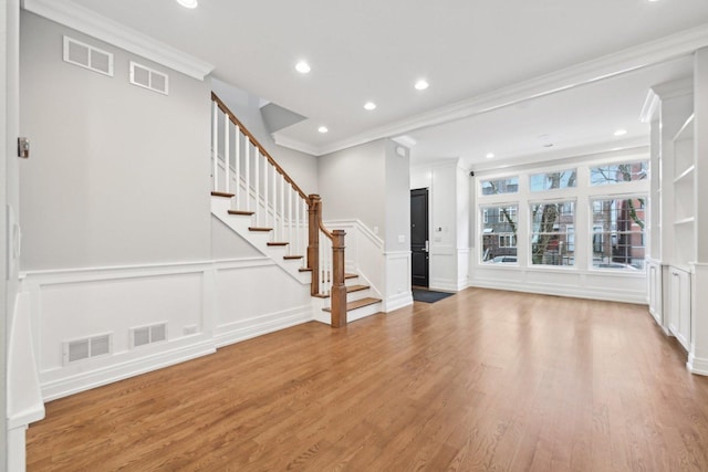 unfurnished living room with wood-type flooring and crown molding