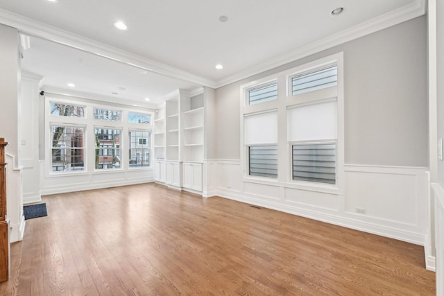 unfurnished living room with light wood-type flooring, built in features, and crown molding