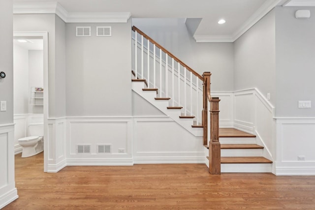 stairs featuring hardwood / wood-style floors and crown molding