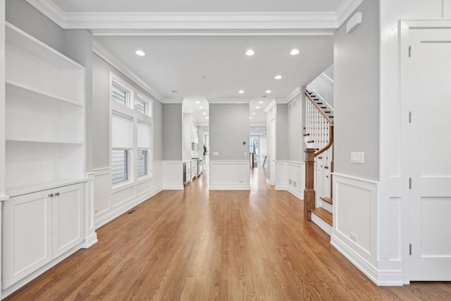 unfurnished living room with light wood-type flooring and ornamental molding