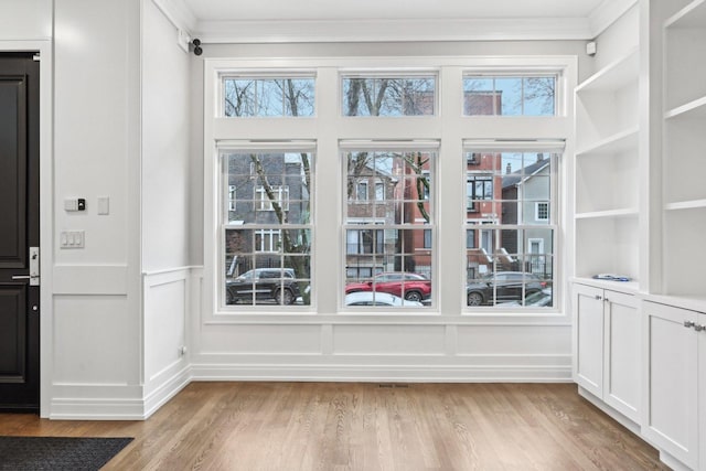 doorway to outside with built in shelves, a wealth of natural light, and light hardwood / wood-style flooring