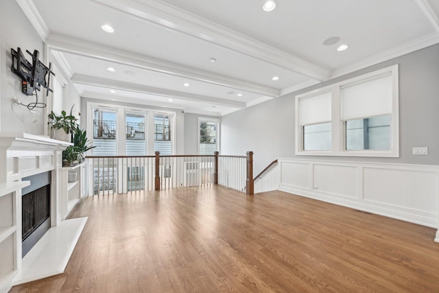 unfurnished living room with beam ceiling, wood-type flooring, and ornamental molding