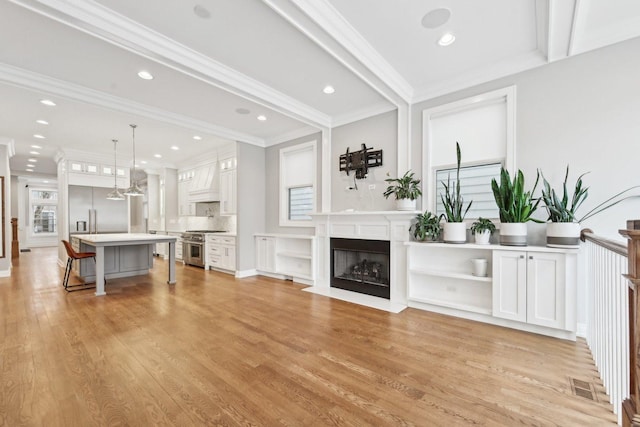 unfurnished living room featuring beamed ceiling, light hardwood / wood-style flooring, and ornamental molding