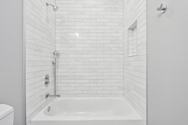 bathroom featuring tiled shower / bath combo and toilet