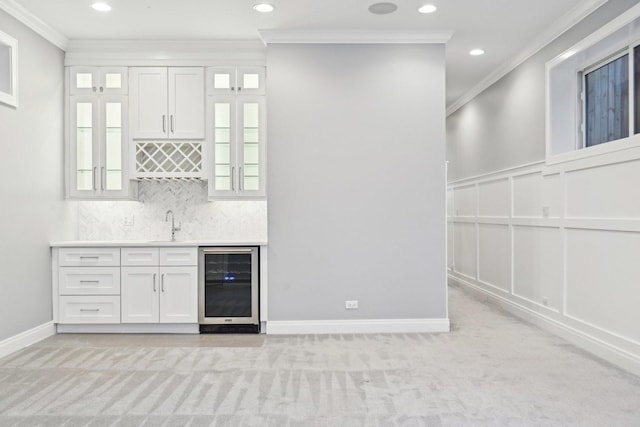 bar with crown molding, white cabinets, beverage cooler, and light colored carpet