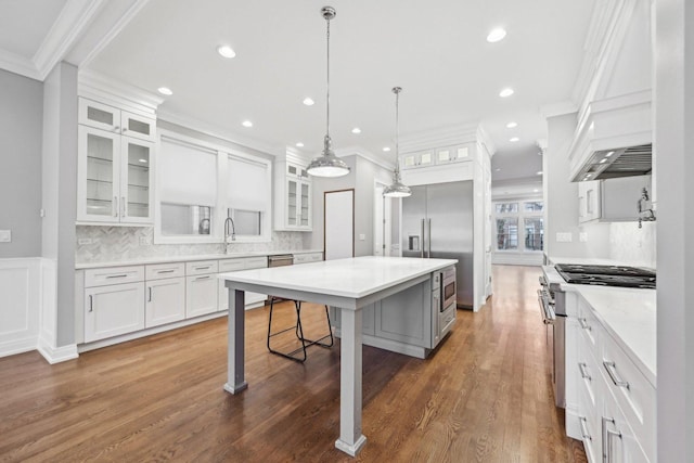 kitchen featuring decorative backsplash, pendant lighting, white cabinets, a center island, and a breakfast bar area