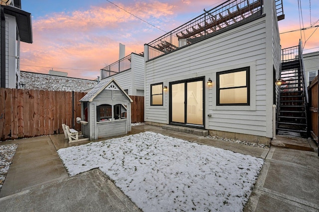 back house at dusk featuring a balcony