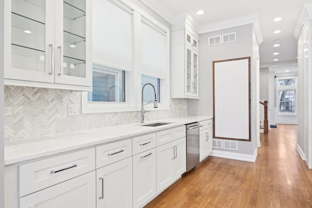 kitchen with light stone countertops, white cabinetry, sink, stainless steel dishwasher, and light hardwood / wood-style floors