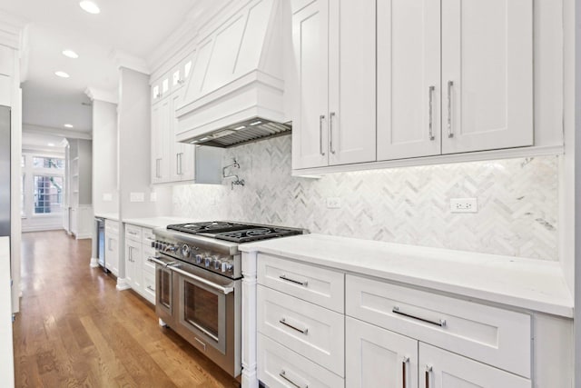 kitchen with premium range hood, white cabinets, crown molding, high end stainless steel range oven, and light stone counters