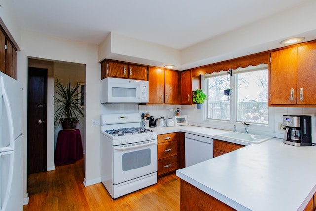 kitchen featuring white appliances, light hardwood / wood-style floors, sink, and decorative backsplash