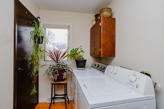 laundry area with cabinets, light hardwood / wood-style floors, and washing machine and dryer