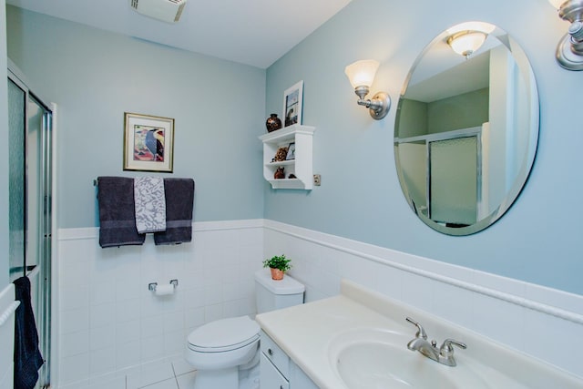 bathroom featuring vanity, toilet, tile walls, and walk in shower