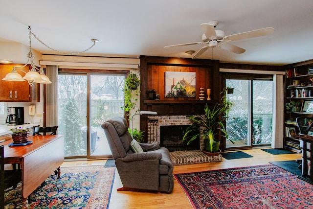 living room with ceiling fan, a fireplace, and light hardwood / wood-style flooring