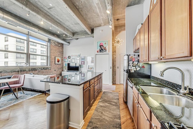 kitchen featuring sink, light hardwood / wood-style flooring, brick wall, stove, and dark stone counters