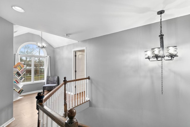 stairway with lofted ceiling, hardwood / wood-style flooring, and a notable chandelier