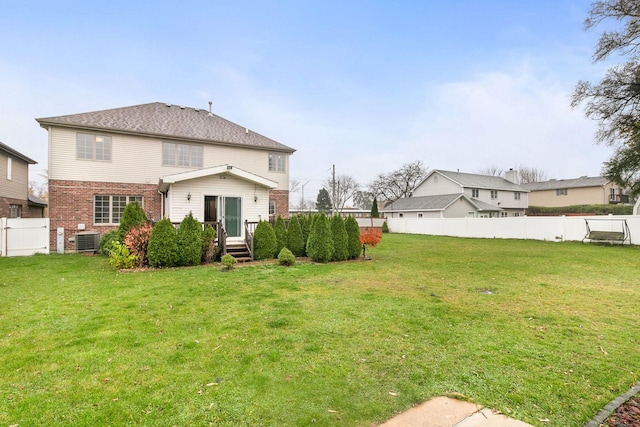 back of property featuring a lawn and central air condition unit