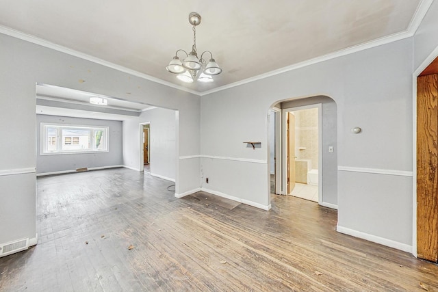 spare room featuring ornamental molding, hardwood / wood-style flooring, and a notable chandelier