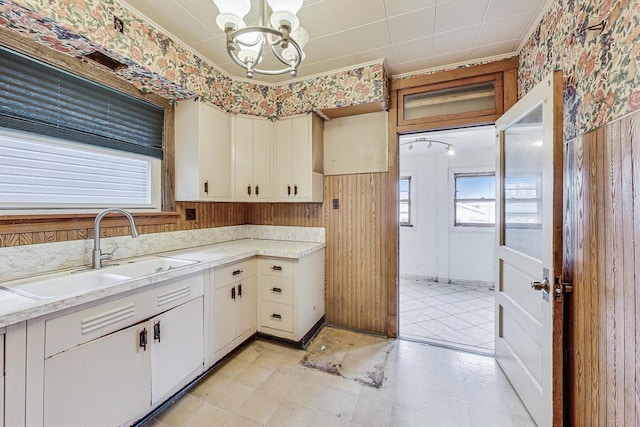 kitchen featuring pendant lighting, an inviting chandelier, wood walls, and sink